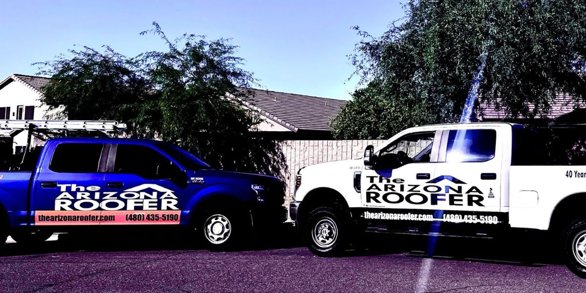 Two branded service trucks from The Arizona Roofer parked in a residential neighborhood.