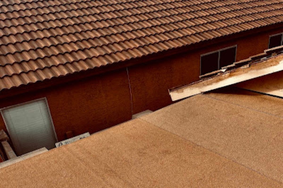 Tile roof next to a flat roof section under repair on a residential home.