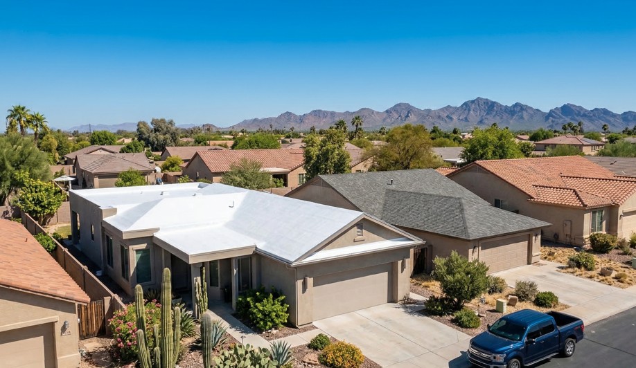 Aerial view of an Arizona home comparing a white spray foam reflective roof coating to traditional dark asphalt shingles under intense Phoenix sun.