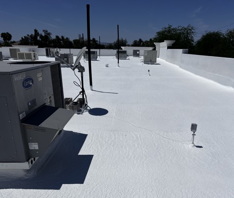 Completed spray foam roof coating on a commercial rooftop in Gilbert, AZ, with HVAC units and roof penetrations